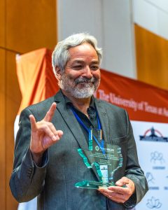 Dr. Campos holding award and raising the hook'em